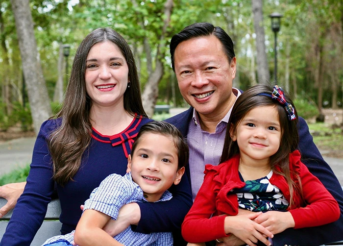 Nick Tran with his wife Valarie and their family in a wooded setting.