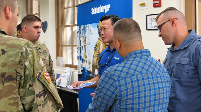 Nick Tran speaking with service members at a Schlumberger event.